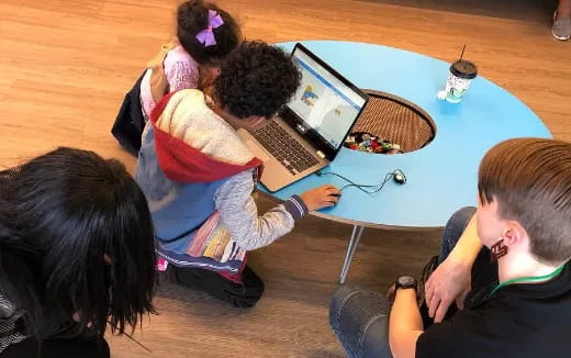 a group of people sitting around a table with a laptop