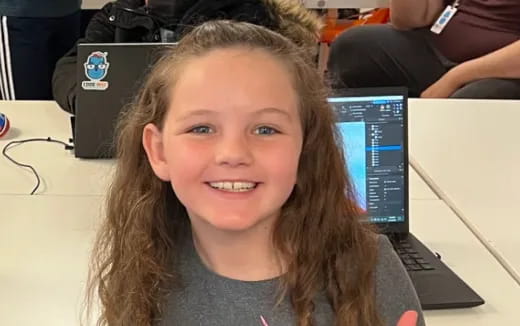 a girl smiling in front of a laptop