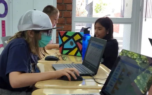 a few young girls working on laptops
