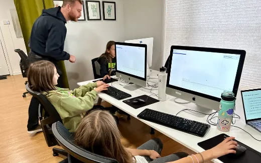 a group of people sitting at a table with computers