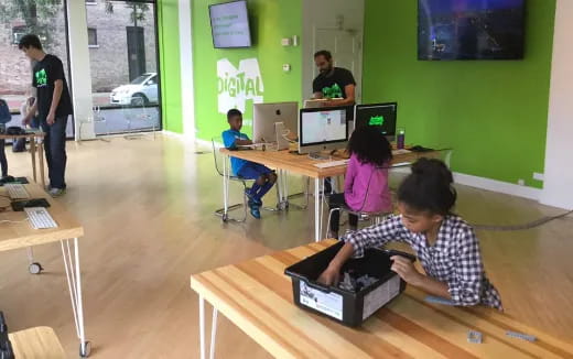 a group of people sitting at a table with computers