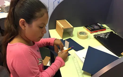 a young girl writing on a book