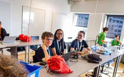 a group of people sitting at tables with laptops