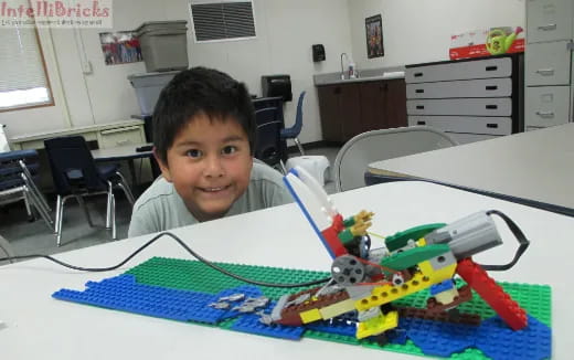 a boy sitting at a table with a toy train