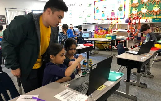 a person and a couple of kids using laptops