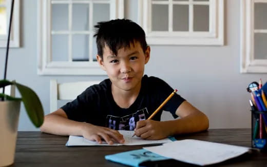 a boy sitting at a desk writing