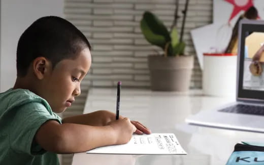 a young boy writing on a piece of paper