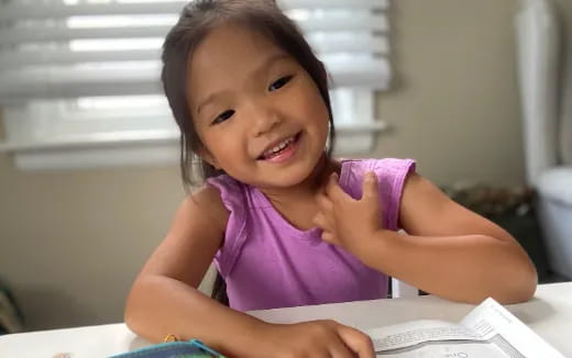 a girl smiling and sitting at a table