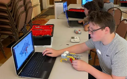 a man sitting at a table with a laptop and a toy gun