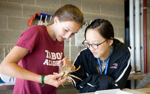 a couple of women looking at a small crab