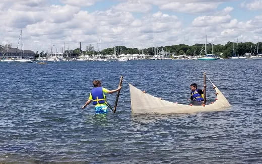 a couple of people on a small sailboat in the water