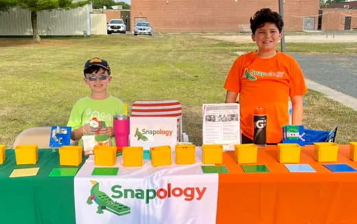 a couple of kids wearing safety goggles and standing next to a table with colorful blocks