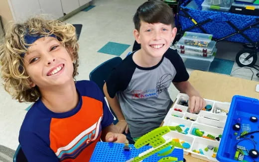 a couple of kids sitting at a table with a toy