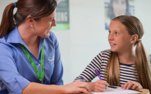 a woman and a girl looking at a paper