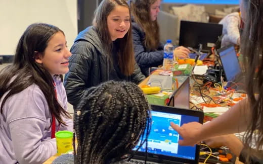 a group of people sitting at a table with computers