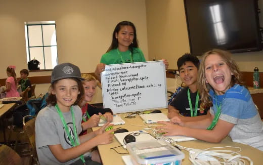 a group of children smiling and holding a sign