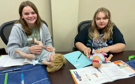 a couple of women sitting at a table with a baby