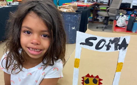 a girl smiling next to a yellow sign
