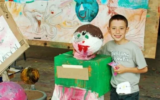 a boy standing next to a cake
