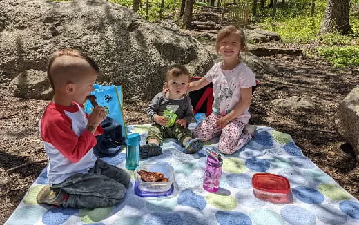 a group of children sitting on a blanket in the sand