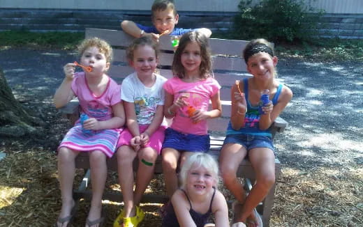 a group of children sitting on a rock by a river