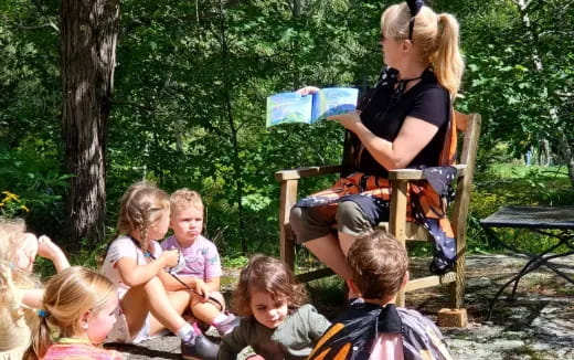 a person sitting in a chair with children around the