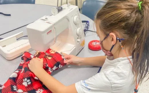 a woman sewing a red flower