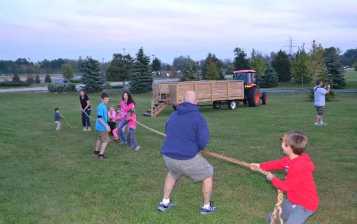 a person and a group of children playing with a stick in a field