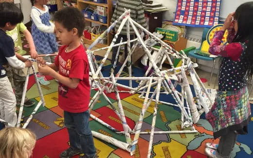 a group of children playing with a model of a tree