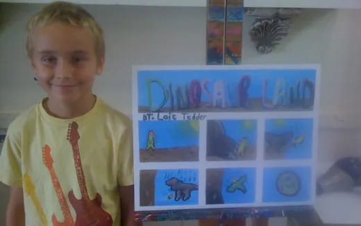 a boy standing next to a computer