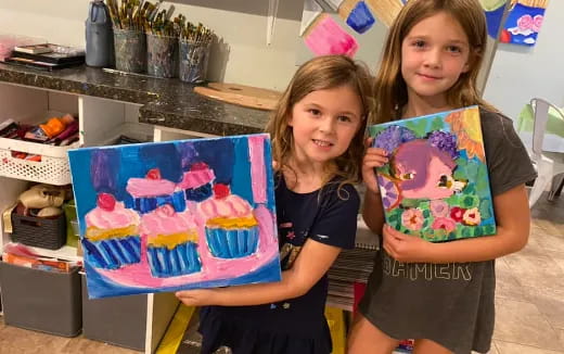 a couple of girls holding a cake