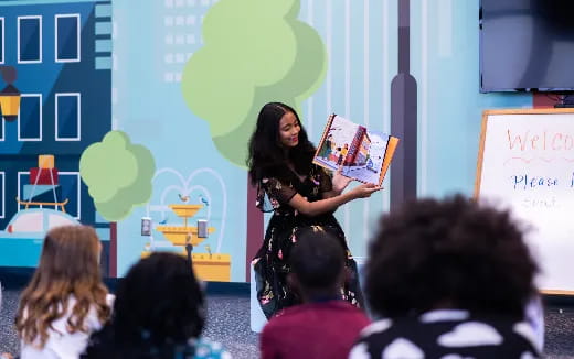 a person reading a book in front of a group of people