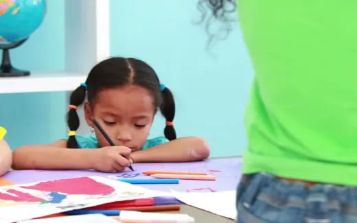 a young girl writing on a piece of paper