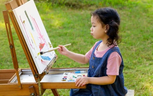 a young girl painting outside