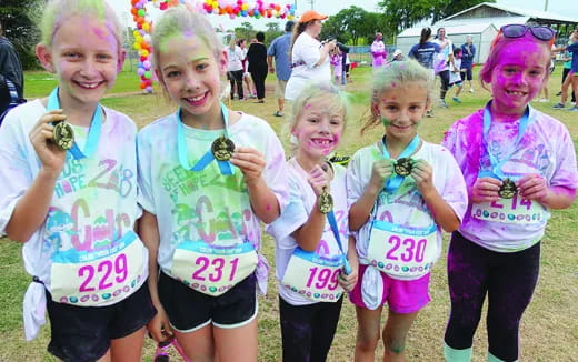 a group of girls wearing matching t-shirts and holding small candies