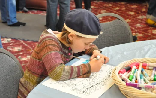 a child sitting at a table writing on a piece of paper