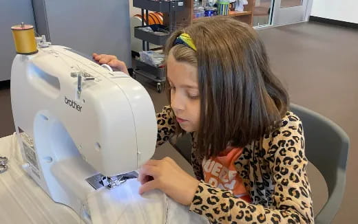 a person sewing a white machine