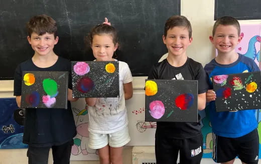 a group of boys holding up artwork