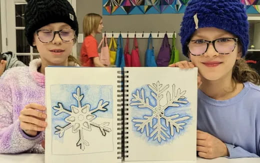 a couple of kids holding up drawings