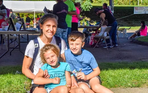 a person and two children sitting on grass