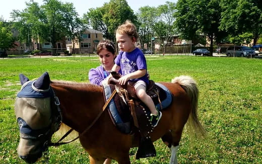a person and a child riding a horse in a park