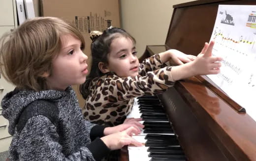 a couple of girls playing piano
