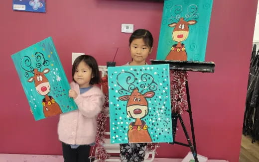 a couple of girls holding paintings