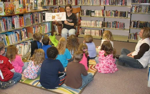 a person reading to a group of children in a library