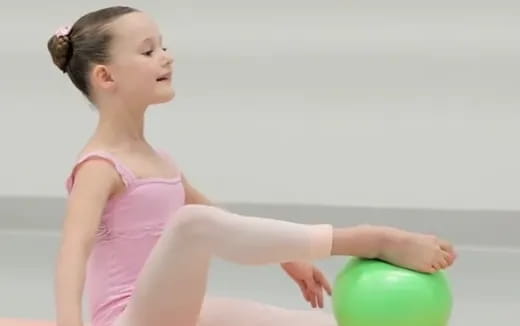 a young girl in a pink swimsuit playing with a ball