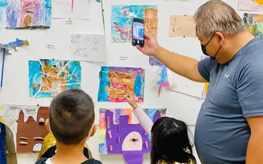 a person showing a boy something on a board