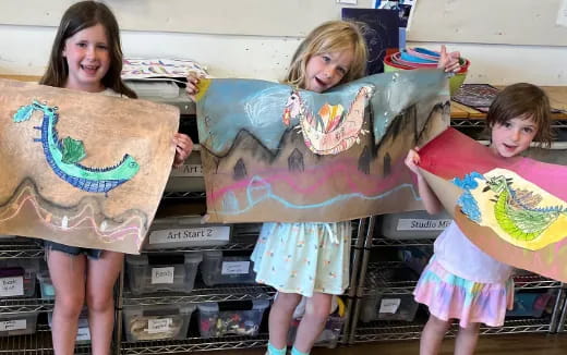 a group of girls holding paintings