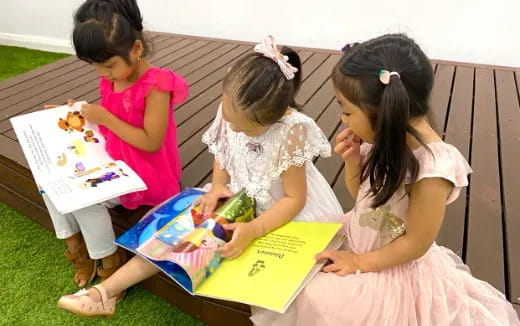 a group of girls sitting on the grass reading a book