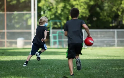 a couple of kids playing with a ball on a field