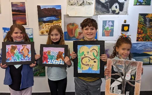 a group of children holding up framed pictures